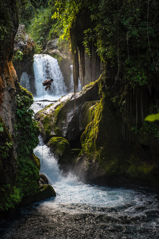 High waterfall with small figure of boy jumping.